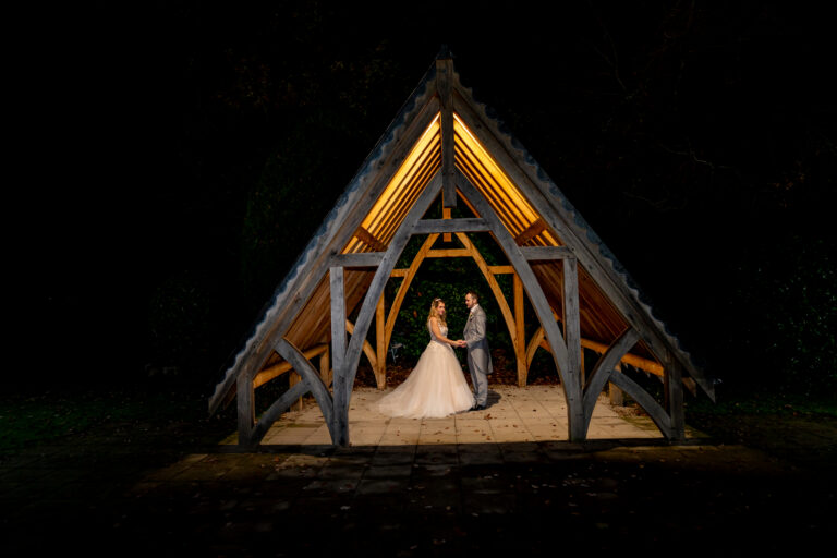 Bride and groom under wooden pavilion at night