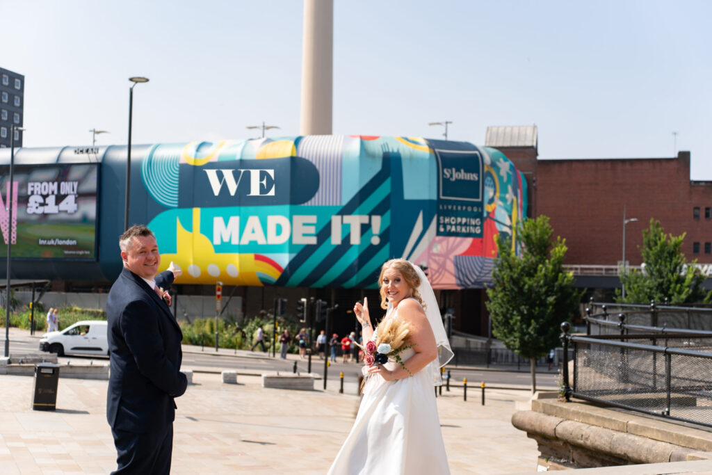 Newlyweds point at colourful Liverpool shopping centre mural