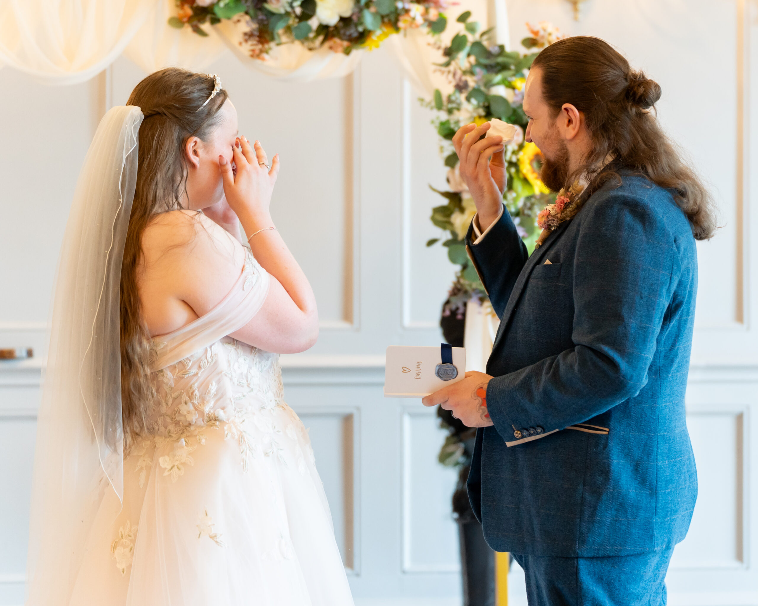 Bride and groom wiping tears during wedding ceremony